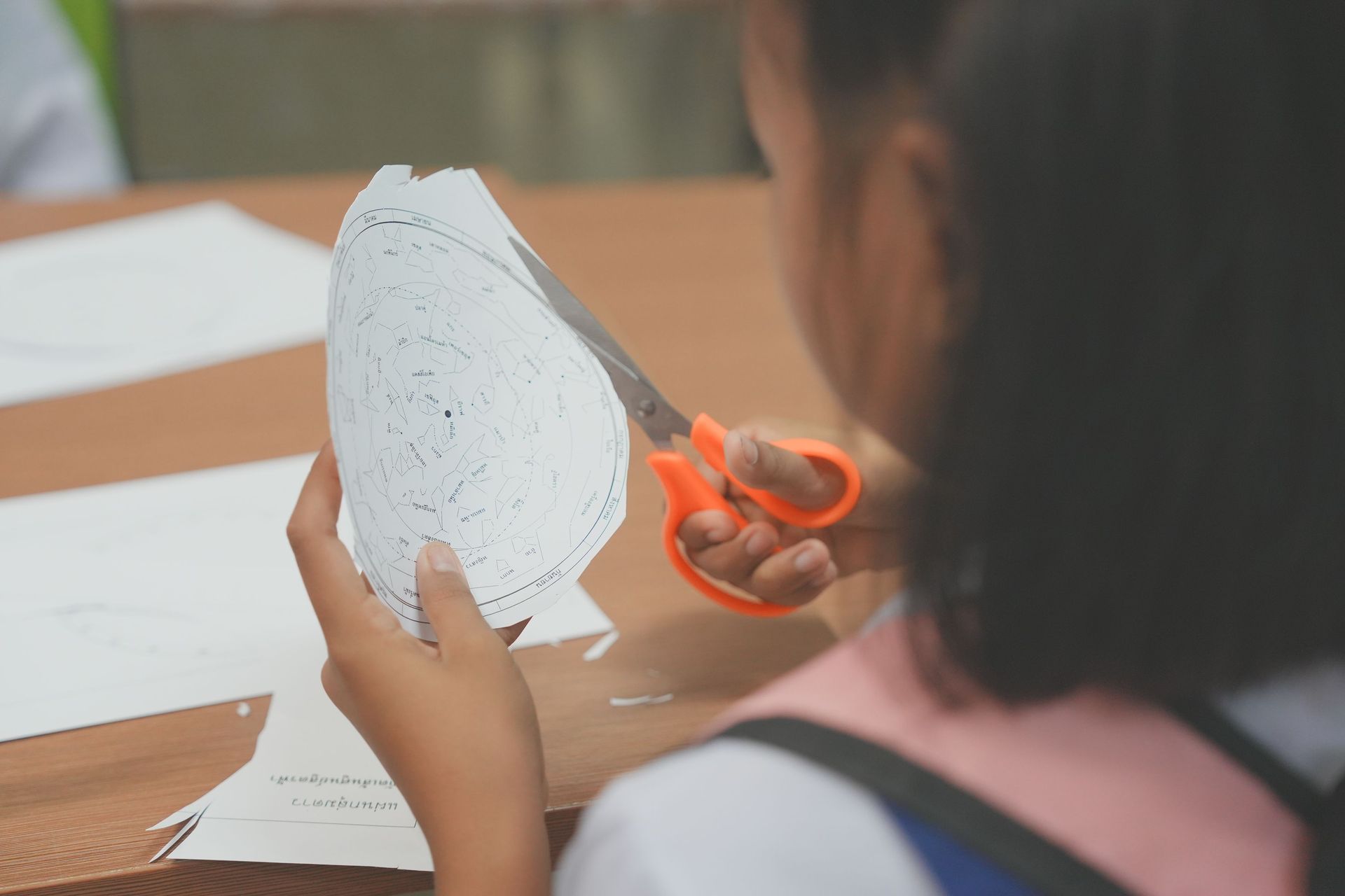 A child using scissors to cut paper in a crafting activity, fostering creativity.